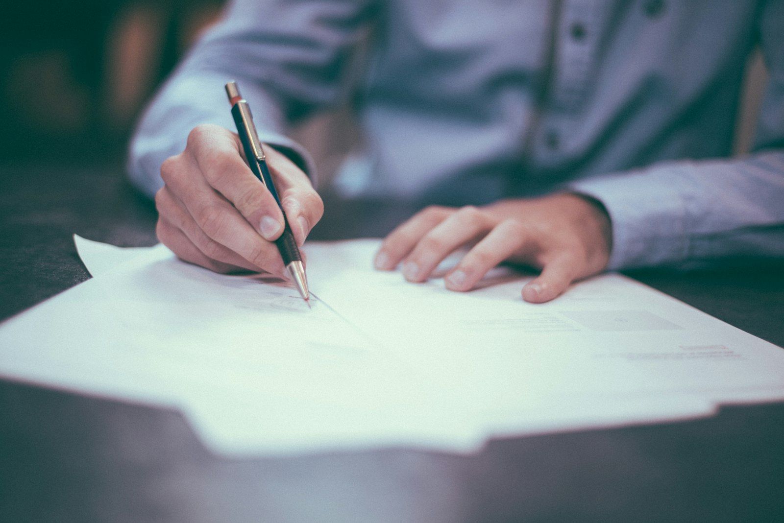 Hands writing on paper documents on a desk