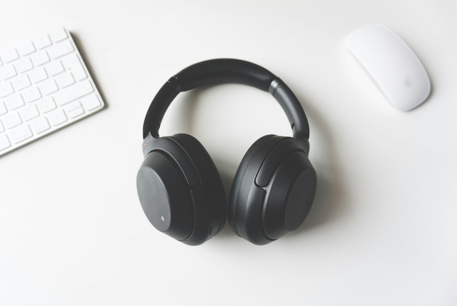 Black headphones on a white desk with keyboard and mouse