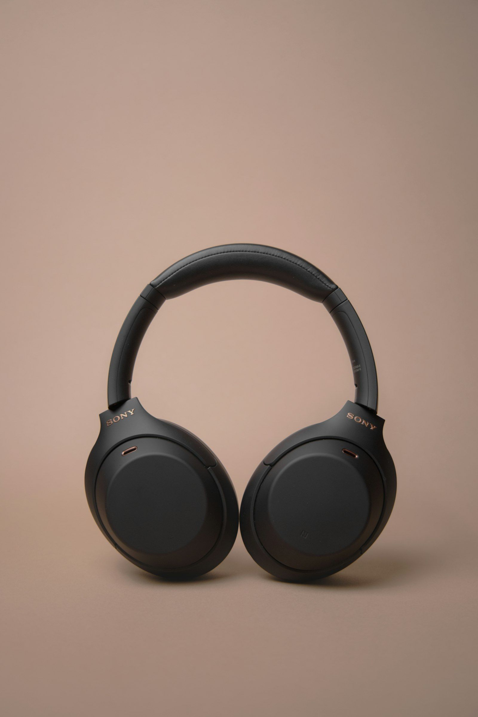 Matte black Sony over-ear headphones on a beige surface