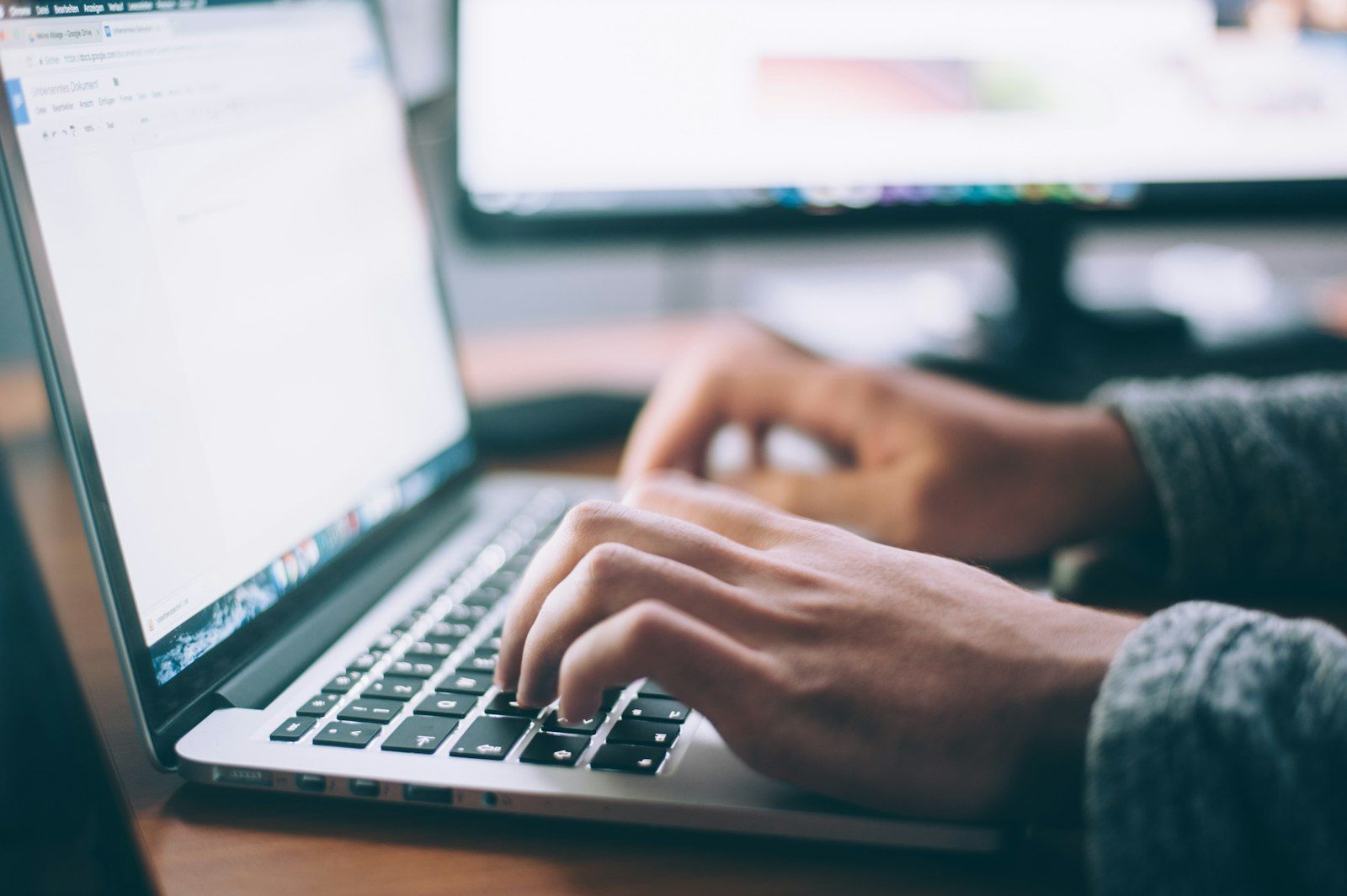 Hands typing on a laptop with a document open in the browser